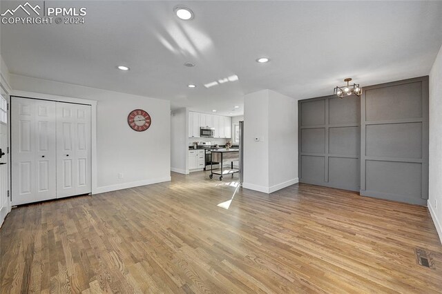 unfurnished living room featuring light hardwood / wood-style floors and a notable chandelier