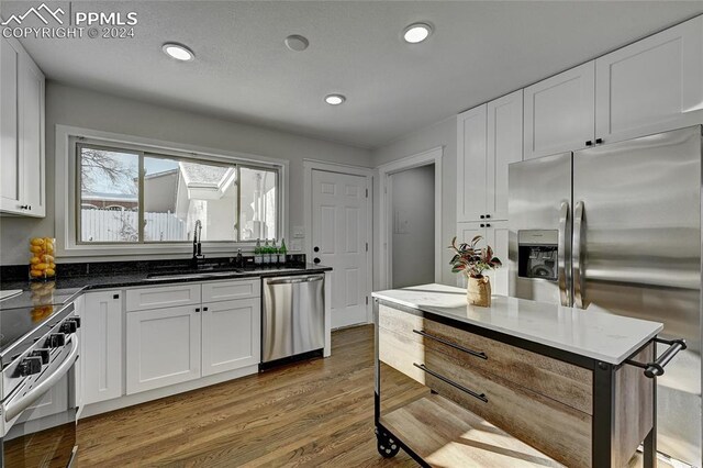 kitchen featuring hardwood / wood-style floors, sink, white cabinetry, and stainless steel appliances