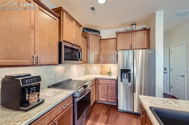 kitchen with decorative backsplash, light stone counters, dark hardwood / wood-style floors, and appliances with stainless steel finishes