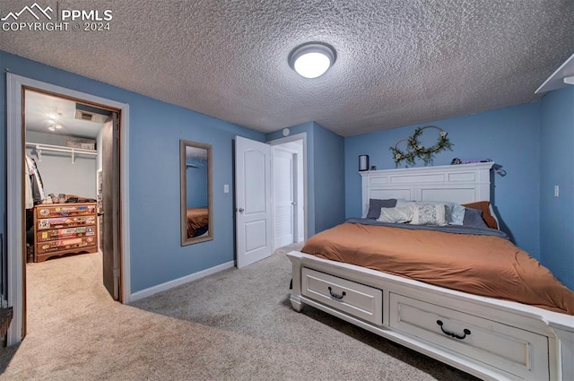 carpeted bedroom featuring a spacious closet, a closet, and a textured ceiling