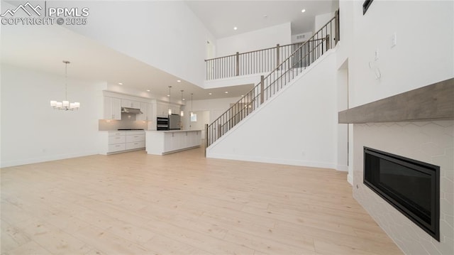 unfurnished living room with a glass covered fireplace, light wood-style flooring, and baseboards