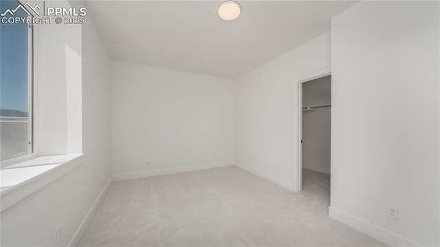 unfurnished bedroom with a spacious closet, carpet floors, and baseboards