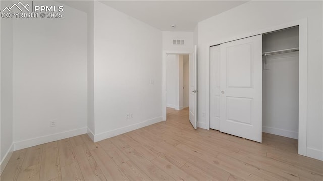 unfurnished bedroom with light wood-type flooring, a closet, baseboards, and visible vents