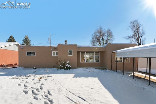 snow covered property featuring a carport