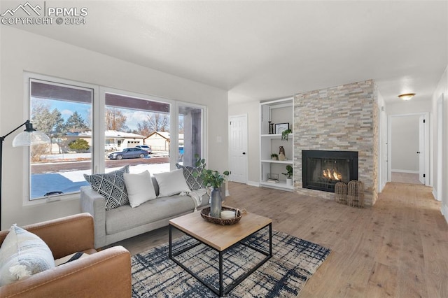 living room with built in shelves, a fireplace, and hardwood / wood-style flooring