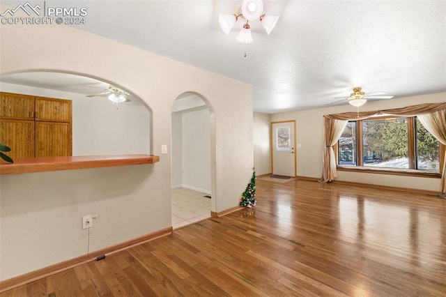 unfurnished living room featuring ceiling fan and light hardwood / wood-style floors