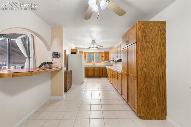 kitchen featuring ceiling fan, white refrigerator, light tile patterned floors, and sink