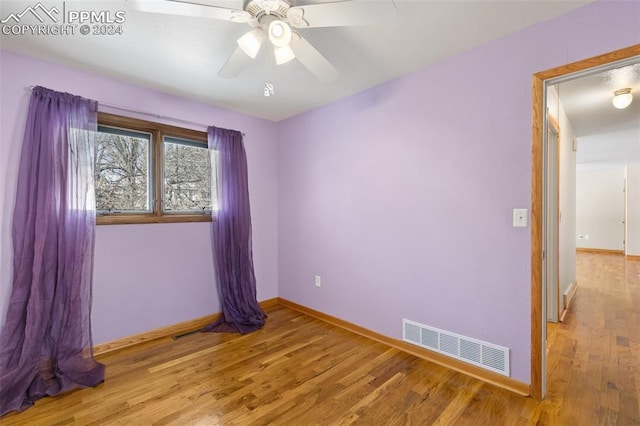 empty room with ceiling fan and light hardwood / wood-style flooring