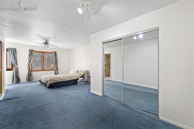 unfurnished bedroom with ceiling fan, dark carpet, and a closet