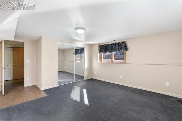 unfurnished bedroom featuring dark carpet and a closet