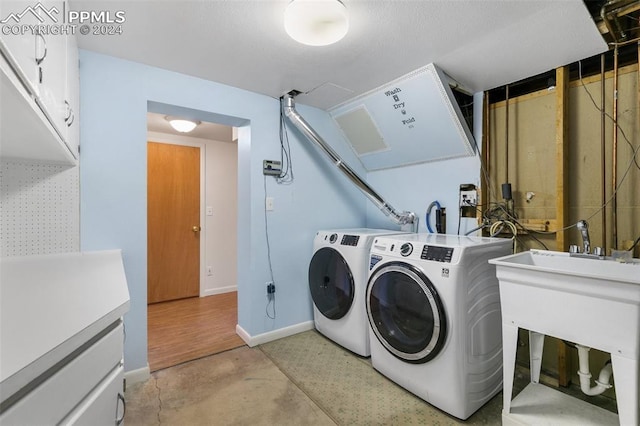 laundry room featuring cabinets, sink, and washing machine and clothes dryer