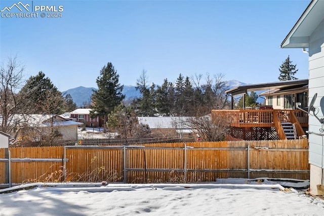 snowy yard with a deck with mountain view