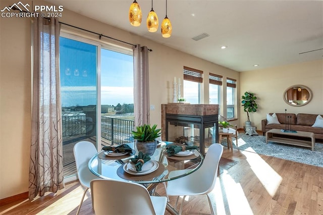 dining room featuring a multi sided fireplace and light hardwood / wood-style floors