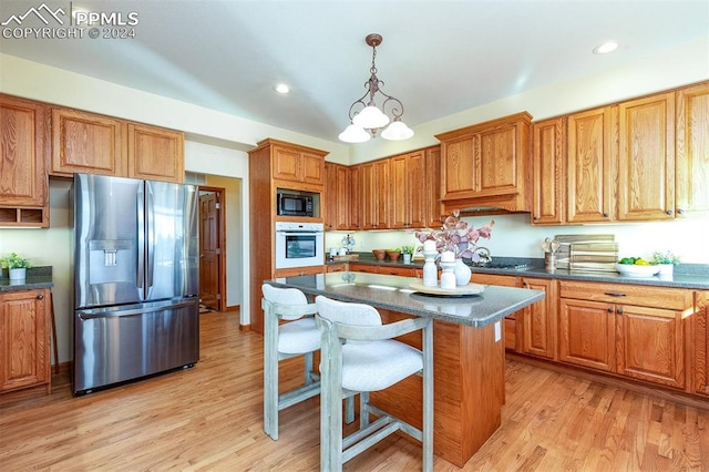 kitchen featuring stainless steel refrigerator with ice dispenser, white oven, black microwave, light hardwood / wood-style flooring, and a chandelier