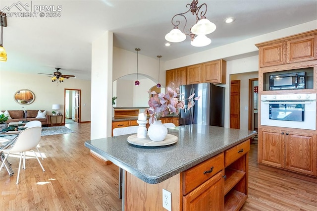 kitchen with oven, stainless steel fridge, light hardwood / wood-style floors, and black microwave