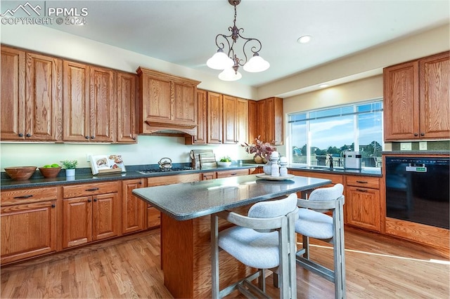 kitchen with black appliances, decorative light fixtures, an inviting chandelier, light hardwood / wood-style floors, and a breakfast bar area