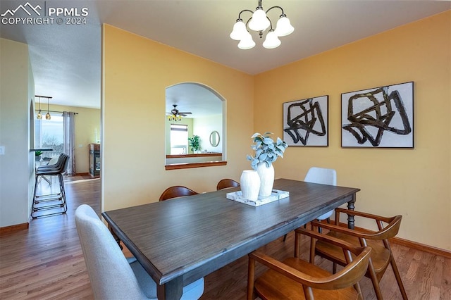 dining area with ceiling fan with notable chandelier and wood-type flooring