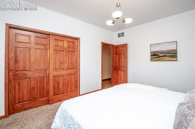 bedroom with a notable chandelier, light carpet, and a closet