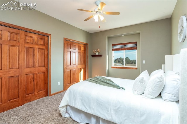 carpeted bedroom featuring ceiling fan and multiple closets