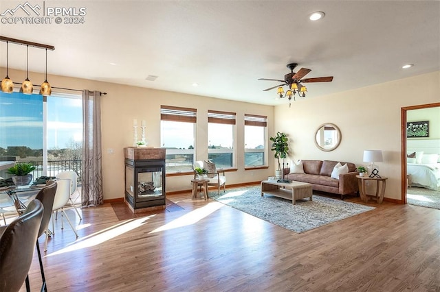 living room with hardwood / wood-style floors, ceiling fan, and a multi sided fireplace