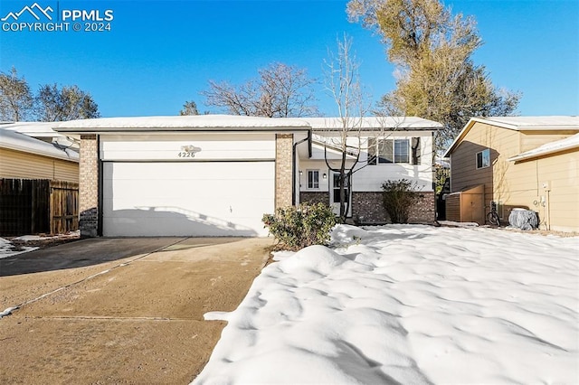 view of front of home featuring brick siding, an attached garage, driveway, and fence