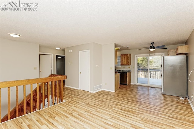 empty room with a textured ceiling, baseboards, visible vents, and light wood-type flooring