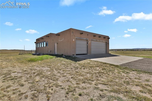 exterior space with a lawn, a rural view, and a garage