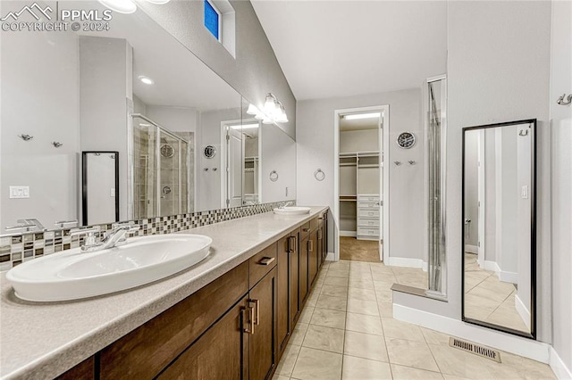 bathroom with tile patterned flooring, vanity, a shower with door, and tasteful backsplash