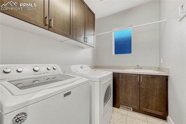 clothes washing area with washer and dryer, light tile patterned flooring, cabinets, and sink