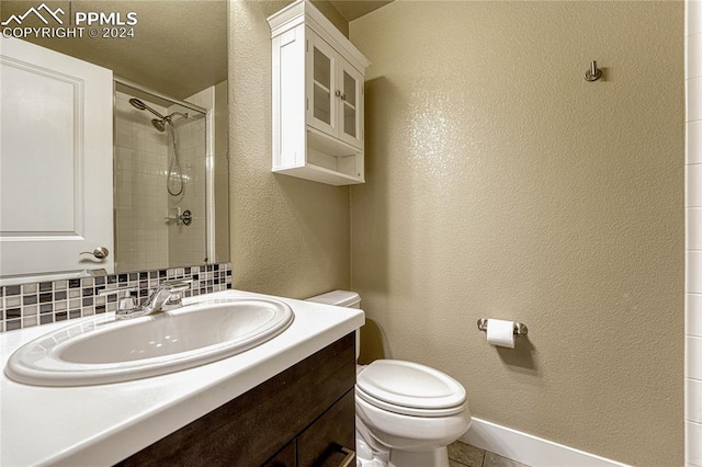 bathroom with decorative backsplash, a tile shower, vanity, tile patterned flooring, and toilet