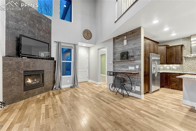 unfurnished living room with a fireplace, light hardwood / wood-style floors, and a high ceiling