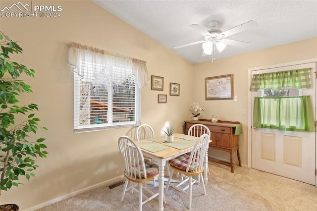 carpeted dining area with a textured ceiling, vaulted ceiling, and ceiling fan