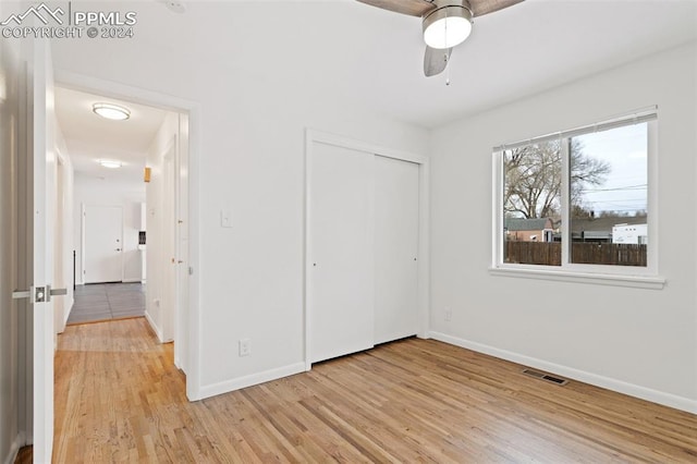 unfurnished bedroom with ceiling fan, a closet, and light wood-type flooring