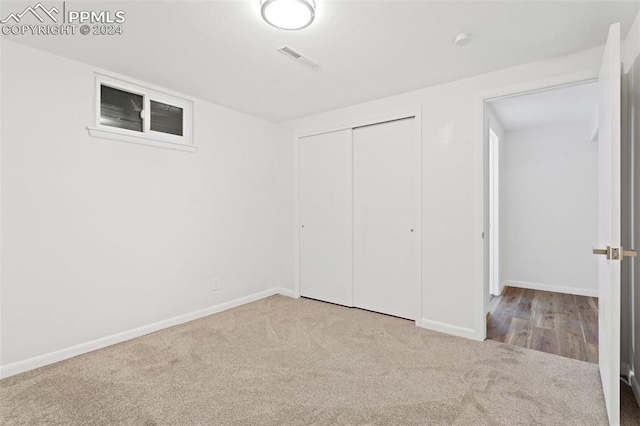 unfurnished bedroom with a closet and light colored carpet