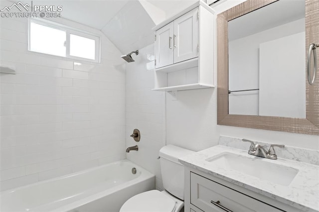 full bathroom featuring toilet, vanity, lofted ceiling, and tiled shower / bath