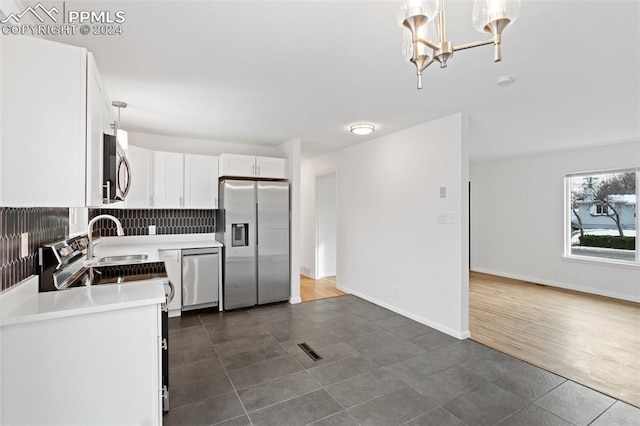 kitchen with white cabinets, decorative backsplash, stainless steel appliances, and hanging light fixtures