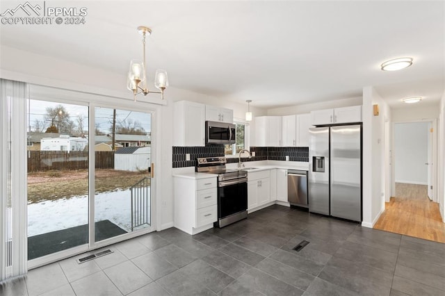 kitchen with decorative backsplash, appliances with stainless steel finishes, sink, decorative light fixtures, and white cabinets