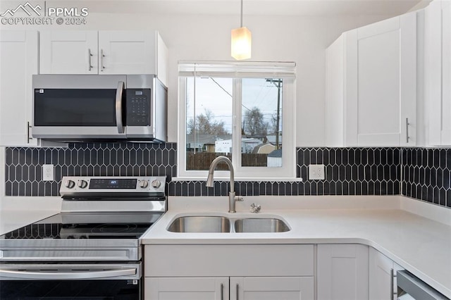 kitchen with white cabinets, decorative light fixtures, sink, and stainless steel appliances