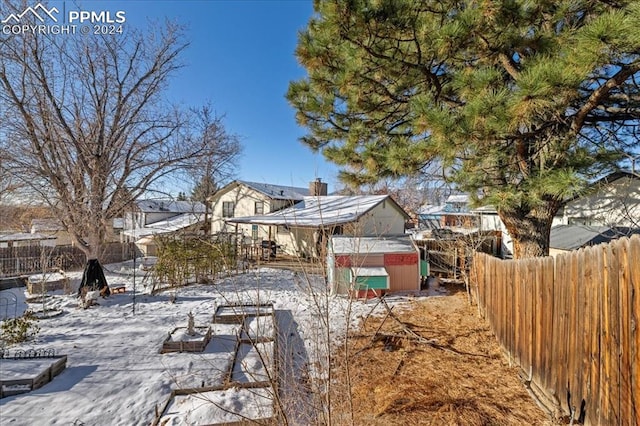 yard covered in snow featuring a storage shed