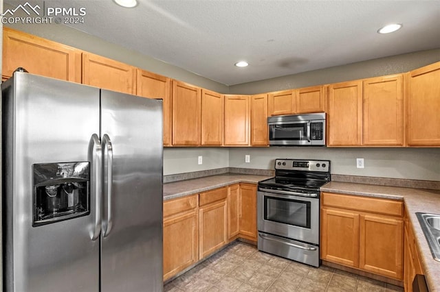 kitchen with a textured ceiling, sink, and appliances with stainless steel finishes