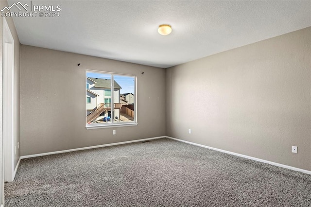 carpeted empty room featuring a textured ceiling