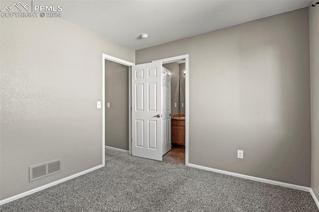 unfurnished bedroom featuring carpet flooring and ensuite bathroom