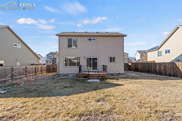 back of property with a lawn and a wooden deck