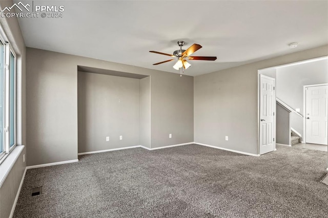 carpeted spare room featuring a wealth of natural light and ceiling fan