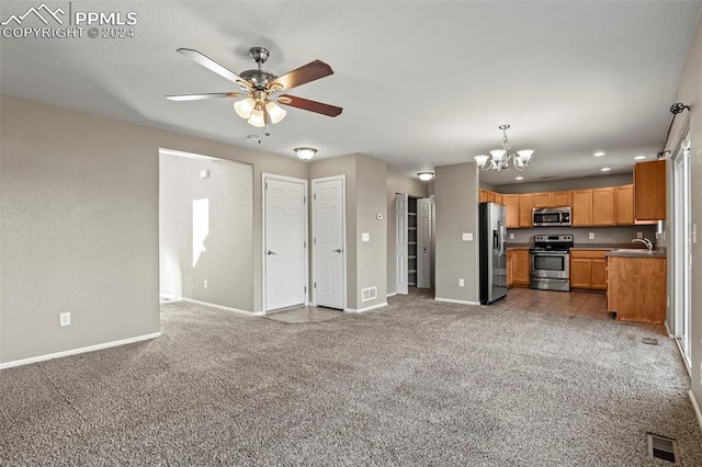 kitchen with sink, dark colored carpet, pendant lighting, ceiling fan with notable chandelier, and appliances with stainless steel finishes