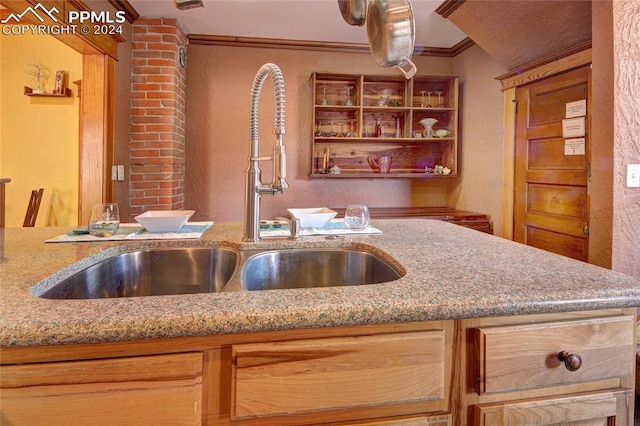 kitchen with light stone countertops, ornamental molding, and sink