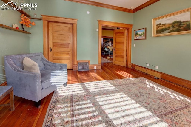 living area with wood-type flooring and ornamental molding