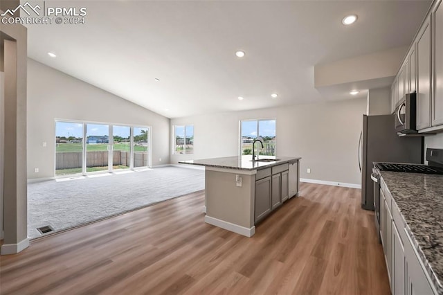 kitchen with sink, stainless steel appliances, gray cabinets, a center island with sink, and carpet