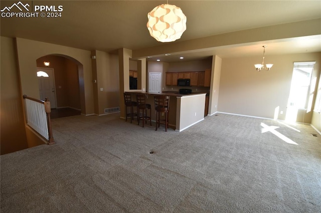 kitchen featuring light carpet, an inviting chandelier, decorative light fixtures, a kitchen bar, and kitchen peninsula