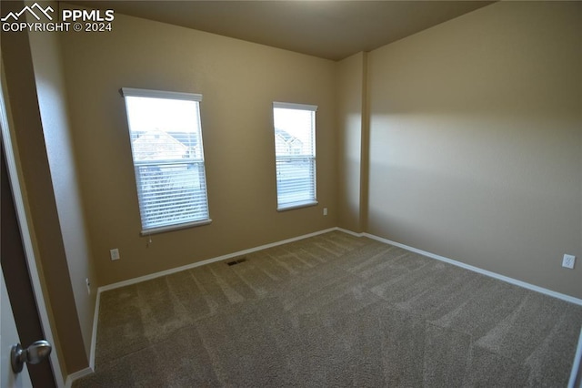 spare room featuring dark carpet